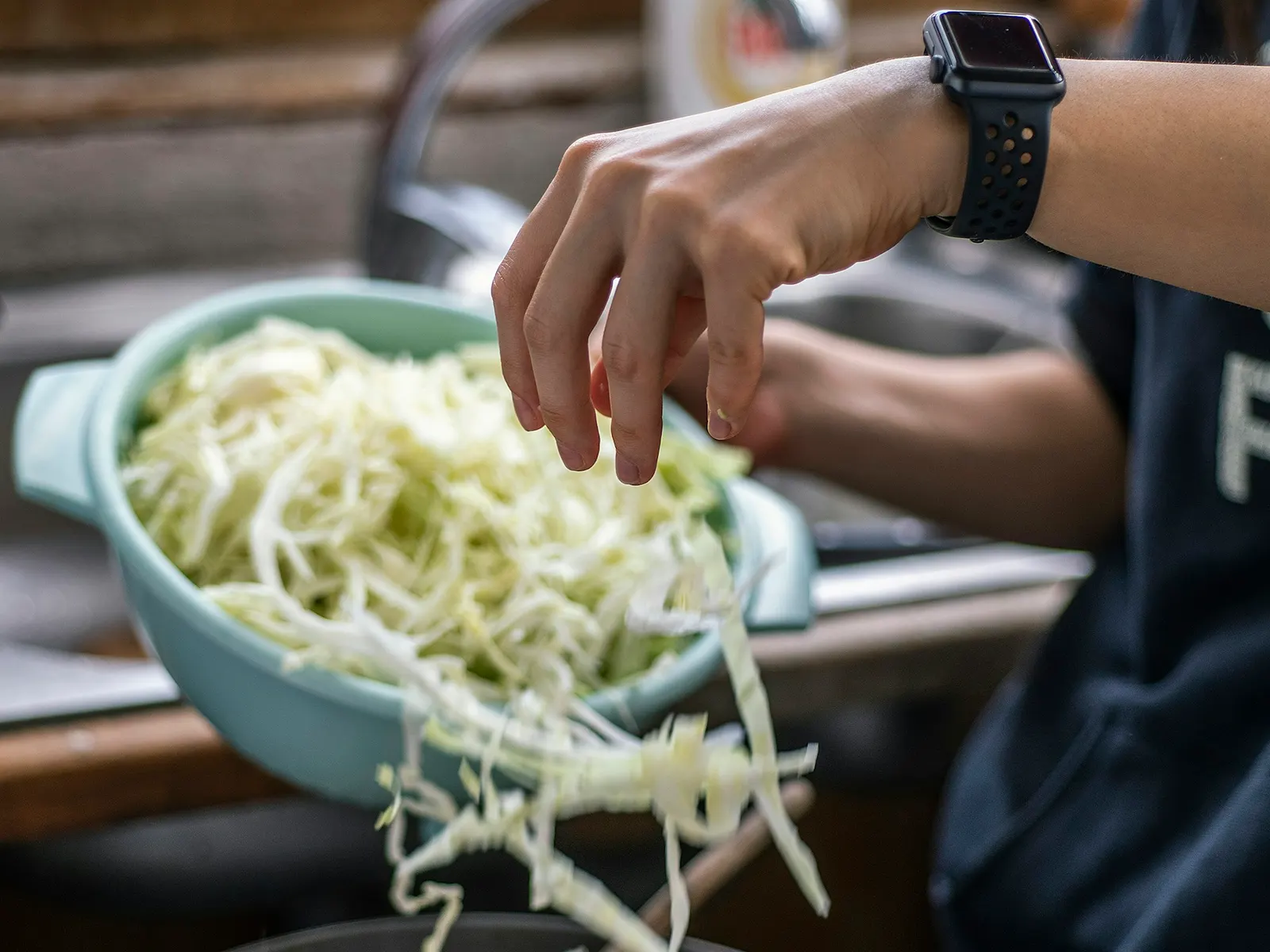 Shredded cabbage going into the pan for egg roll in a bowl