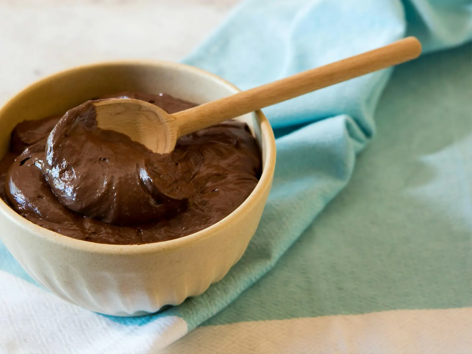 Bowl of chocolate protein pudding with a wooden spoon